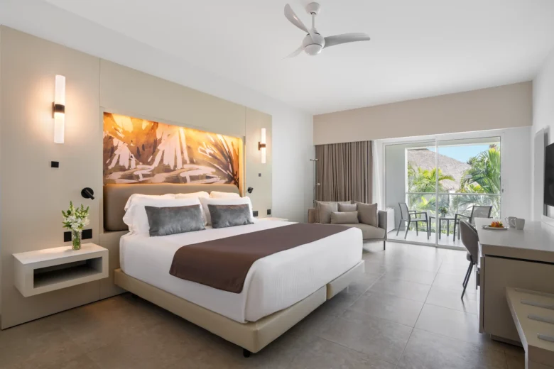 Allure Junior Suite with king bed and private balcony overlooking lush tropical gardens at Breathless Punta Cana Resort.