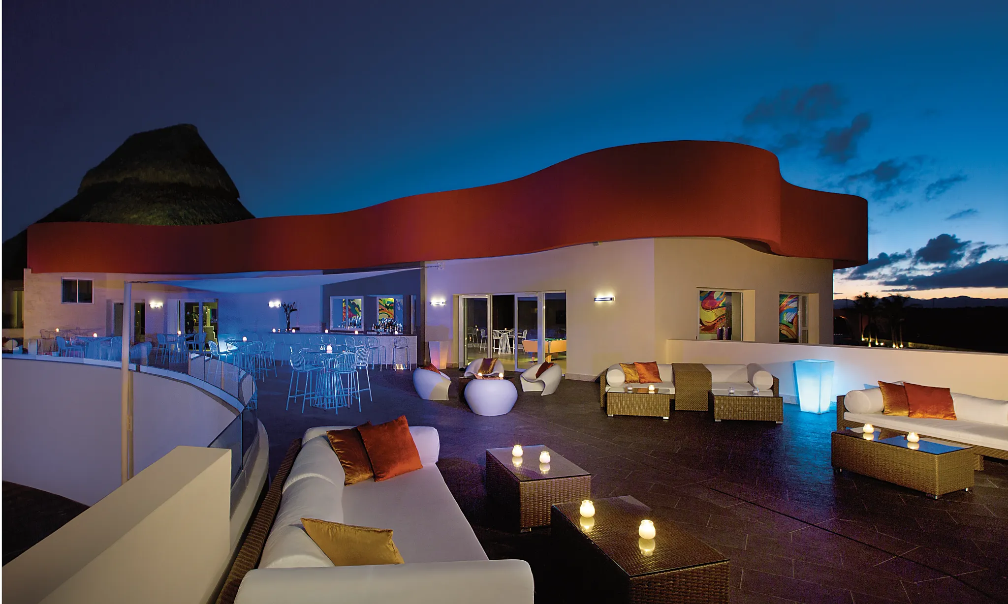 Rooftop lounge seating at Breathless Punta Cana with modern furniture and ambient lighting overlooking the resort at night.