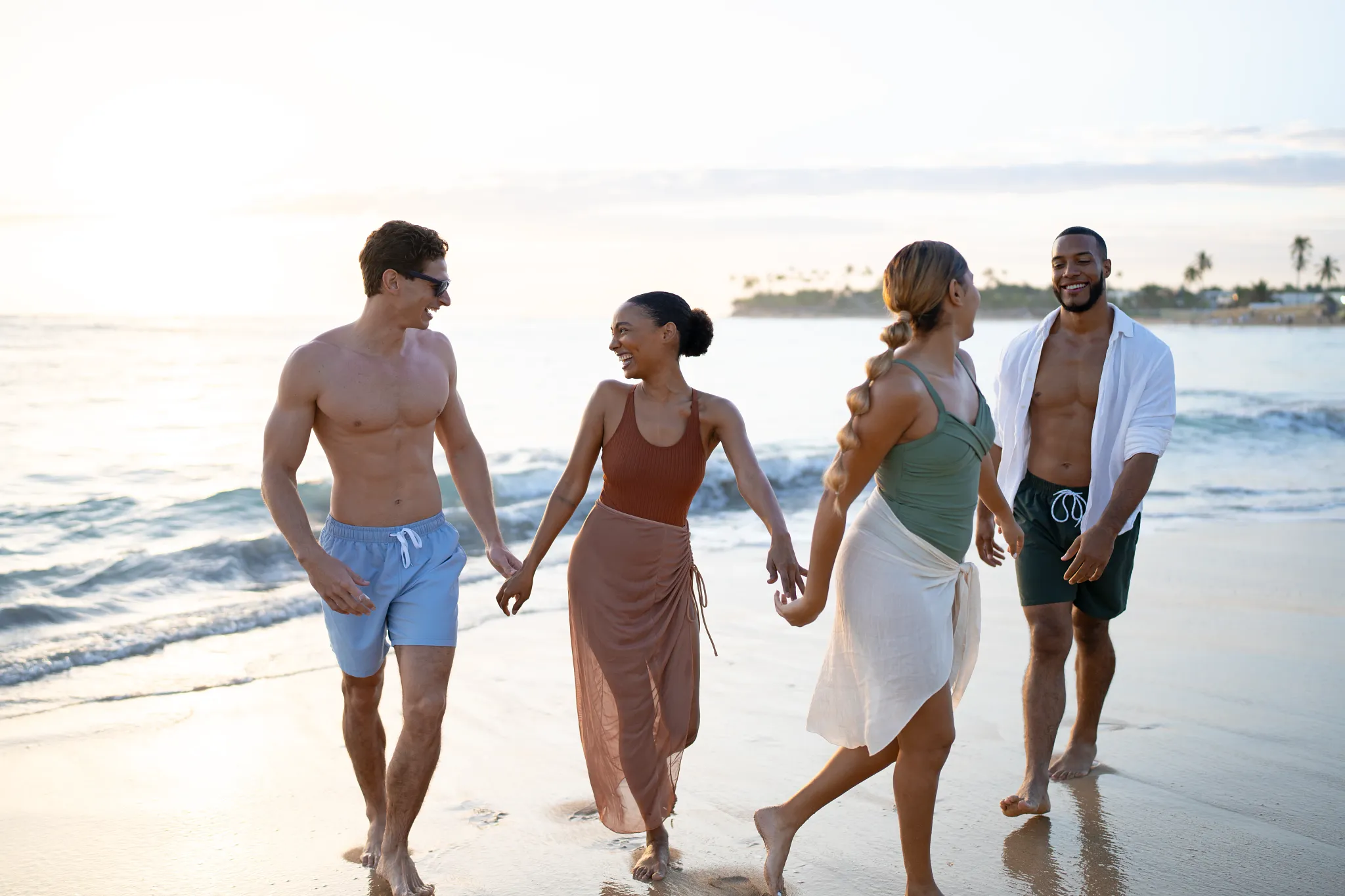 Group of friends walking along the shoreline at Breathless Punta Cana during a sunny beach day.