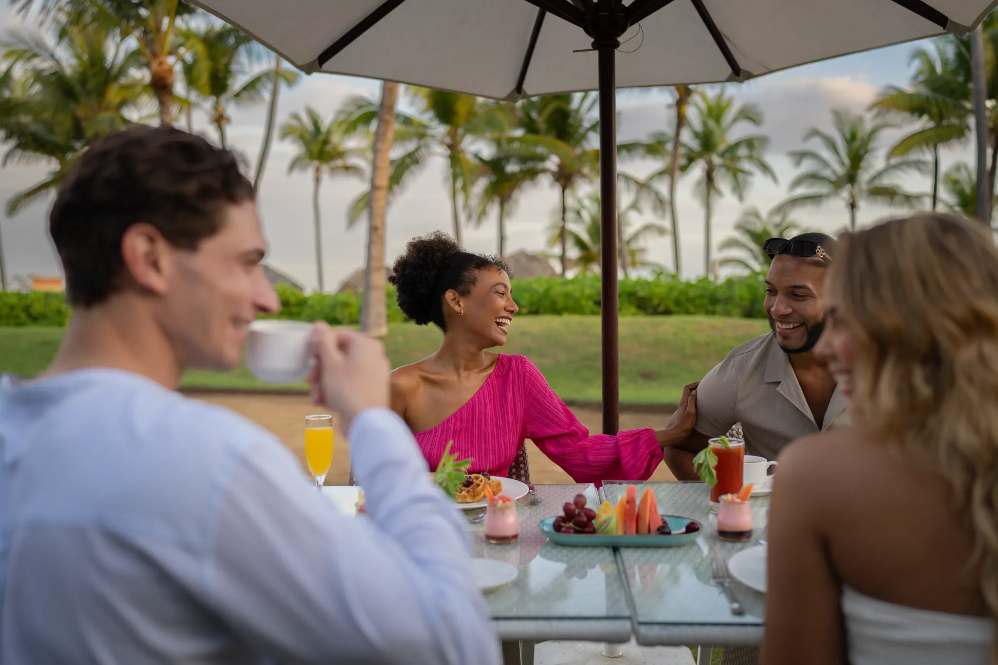 Group of friends enjoying outdoor dining at Breathless Punta Cana surrounded by palm trees and tropical scenery.