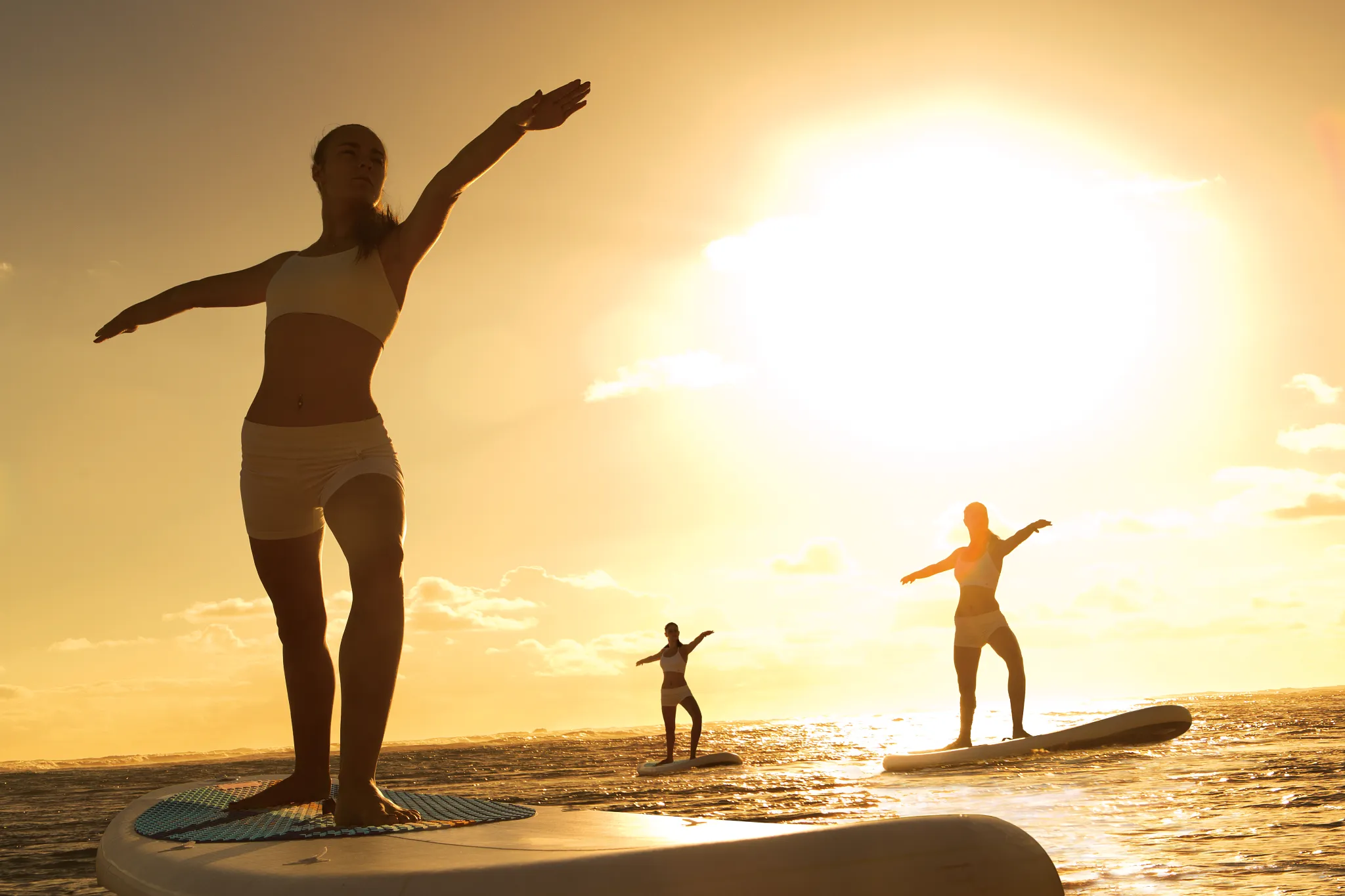 Guests practicing paddle yoga on the ocean at Breathless Punta Cana during golden hour.
